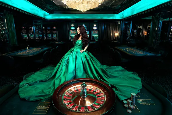 JLWAFA — A high-class gaming experience without limits A woman in a luxurious green gown next to an ornate roulette wheel, capturing the upscale casino mood of JLWAFA.